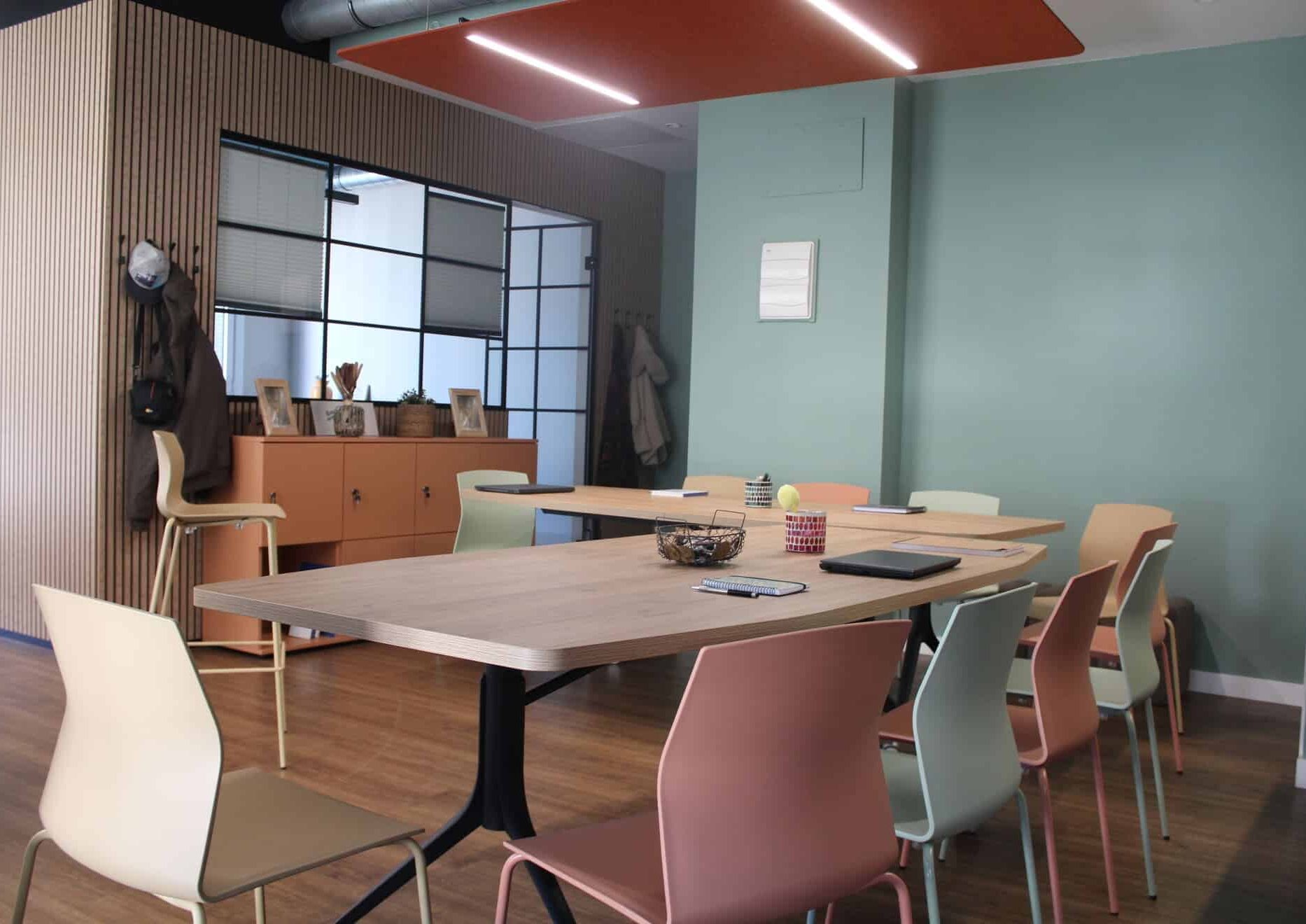 Sala de eventos Kbiak en Amara con mesas dispuestas en forma de L y sillas de colores cálidos.