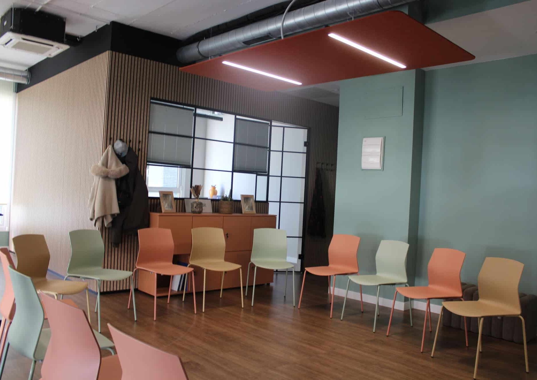 Sala de eventos Kbiak en Amara configurada en forma de U con mesas de madera, sillas de colores cálidos y zona de office al fondo.