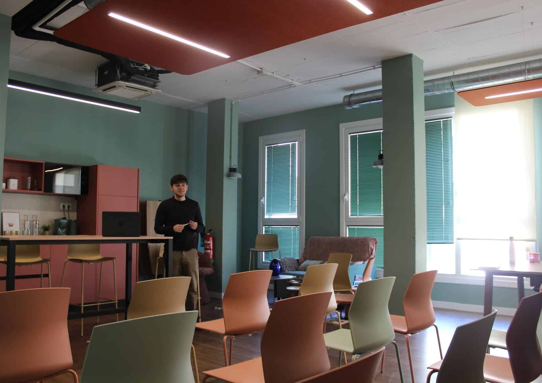 Ponente dando una charla en la sala de eventos Kbiak en Donostia, con zona de office al fondo.