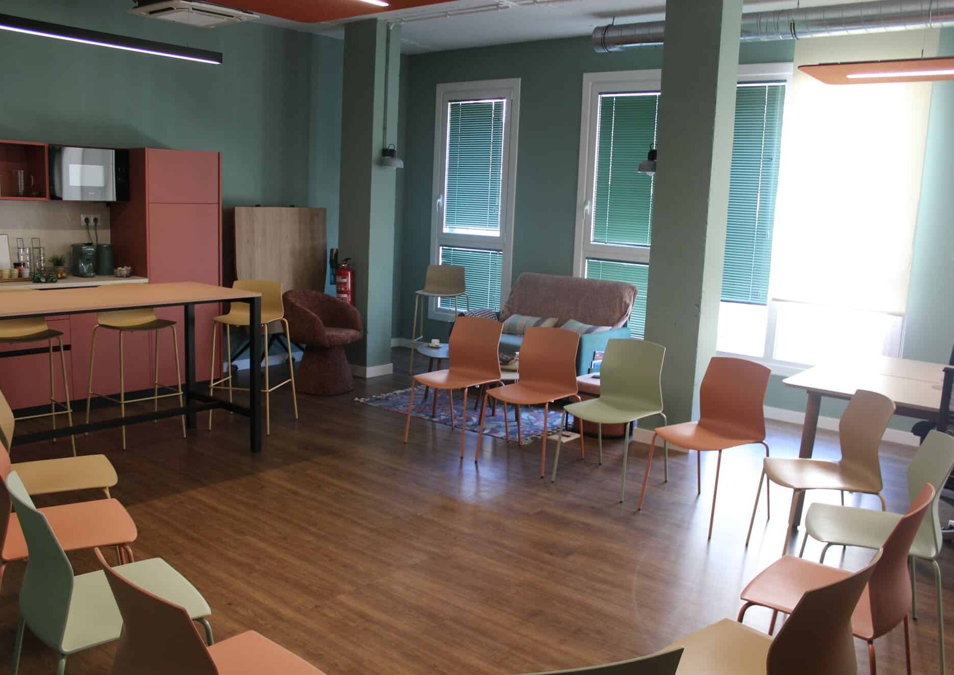 Sala de eventos organizada en forma de U con acceso directo a zona de cocina y café en Donostia.